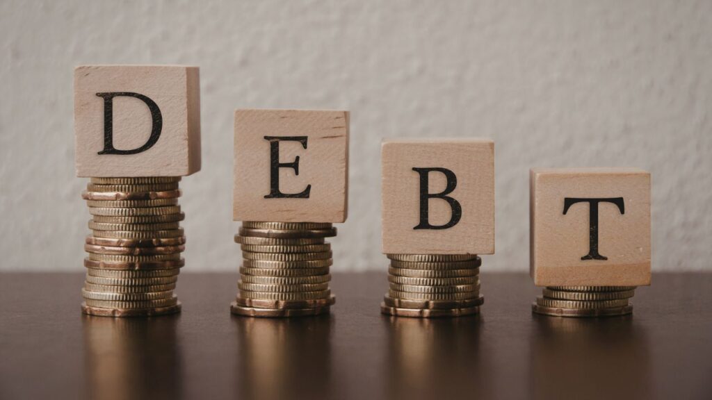 letters that spell "debt" on stacks of coins for someone wondering how to file Chapter 7 with no money