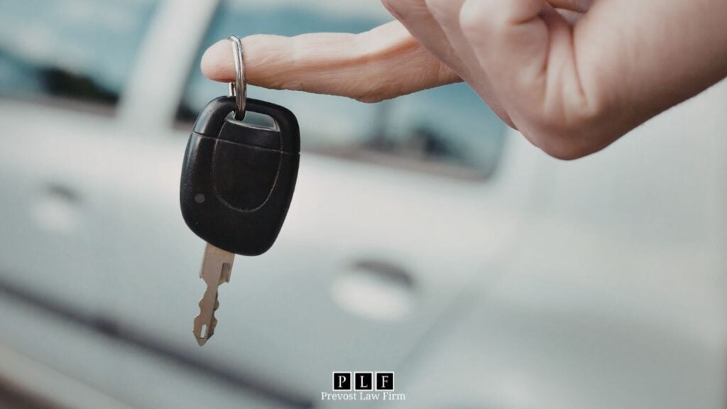 A person's hand dangling a key for voluntary repossession.