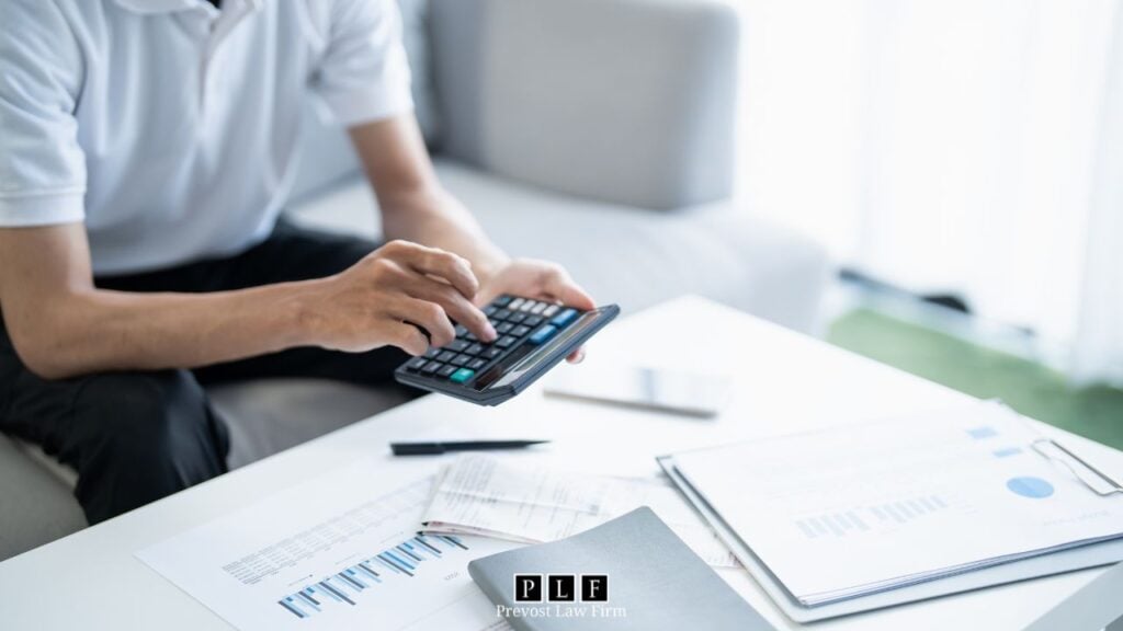 A man with papers in front of him using a calculator to figure out chapter 7 bankruptcy income requirements.