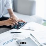 A man with papers in front of him using a calculator to figure out chapter 7 bankruptcy income requirements.